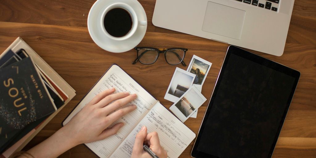 person holding ballpoint pen writing on notebook