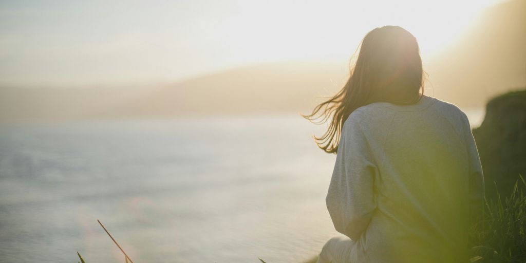 woman wearing gray long-sleeved shirt facing the sea