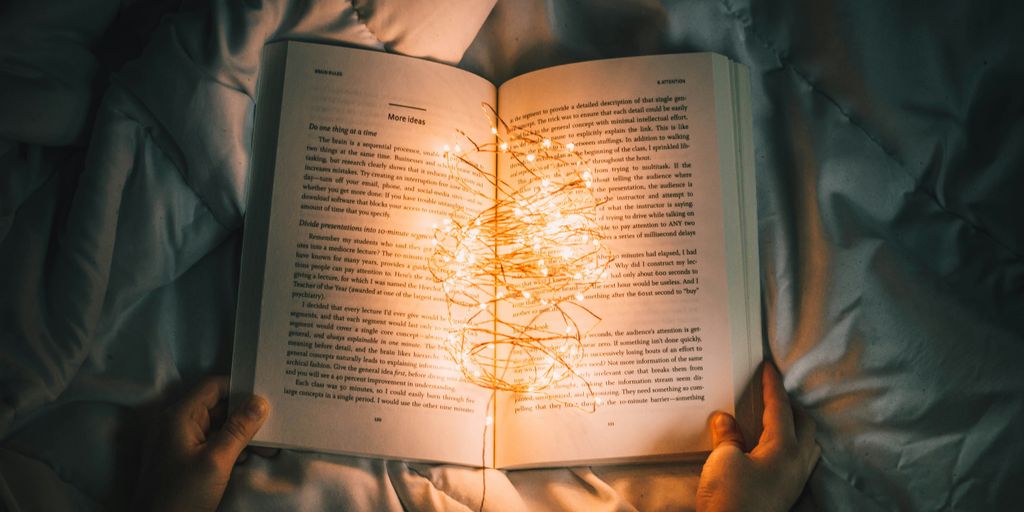 person holding string lights on opened book